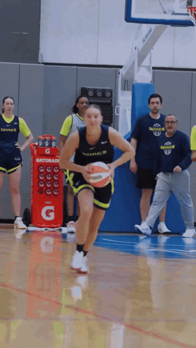 A Woman Dribbles A Basketball In Front Of A Gatorade Cooler GIF