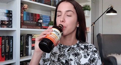 A Woman Drinking From A Bottle That Says Brew On The Label GIF
