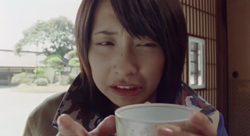 a woman drinking from a small white cup