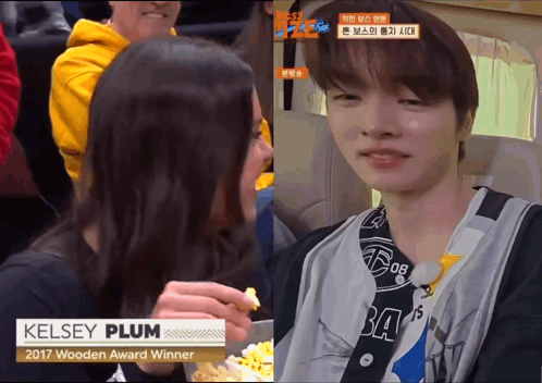 A Woman Eating Popcorn Next To A Man With The Name Kelsey Plum On His Shirt GIF