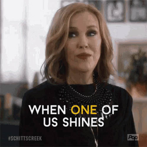 A Woman From Schitt 'S Creek Is Smiling And Saying `` When One Of Us Shines '' GIF