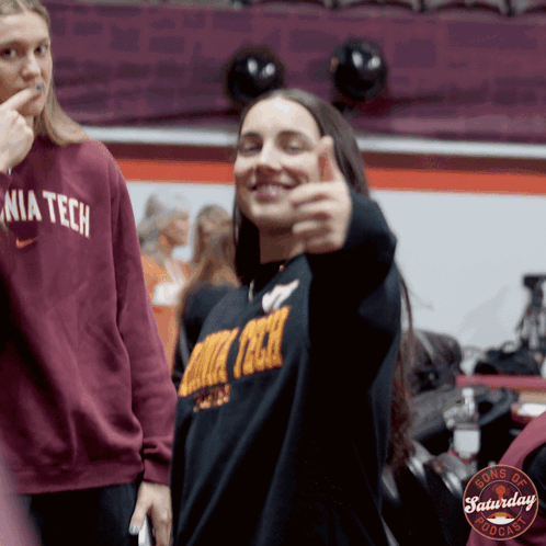 a woman giving a thumbs up wearing a sweater that says nia tech