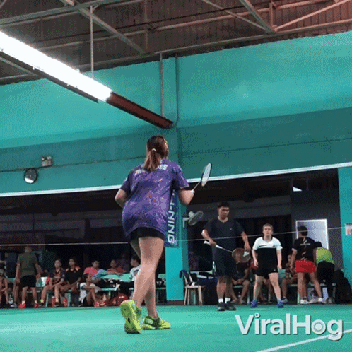 A Woman Holding A Badminton Racket In Front Of A Li Ning Banner GIF