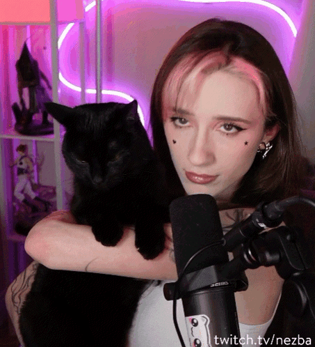 A Woman Holding A Black Cat In Front Of A Microphone With Twitch.tv/nezba On The Bottom Right GIF
