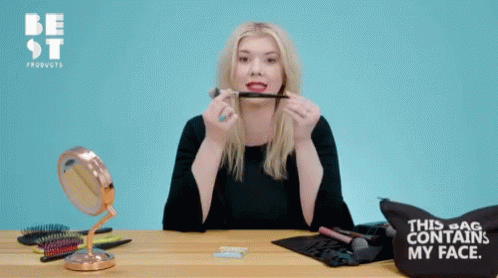 A Woman Holding A Blush Brush In Front Of A Bag That Says " This Bag Contains My Face " GIF