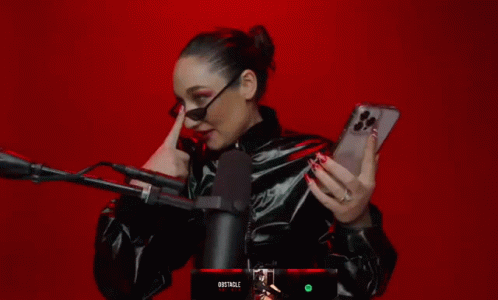 A Woman Holding A Cell Phone In Front Of A Microphone With The Word Obstacle On The Bottom GIF