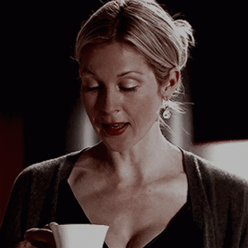 A Woman Holding A Cup Of Coffee In Her Hand GIF