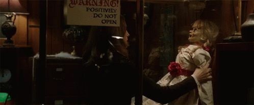 A Woman Holding A Doll In Front Of A Warning Sign GIF