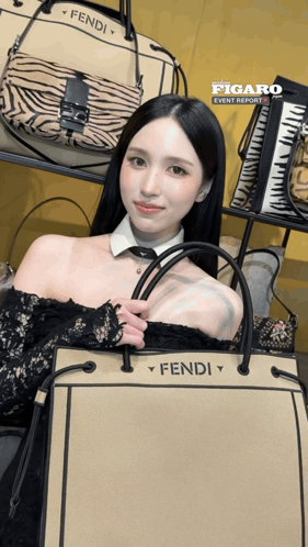 a woman holding a fendi purse in front of a display of handbags