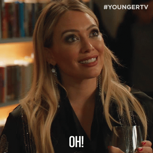 A Woman Holding A Glass Of Wine And Saying Oh GIF