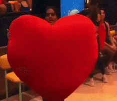 A Woman Holding A Large Red Heart Pillow GIF