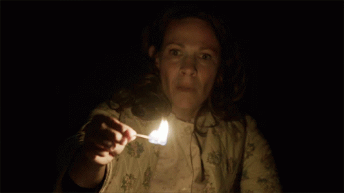 A Woman Holding A Lit Match In Her Hand GIF