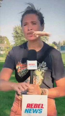 A Woman Holding A Microphone And A Rebel News Sign GIF