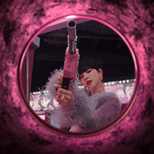 A Woman Holding A Pink Gun In Front Of A Pink Background GIF