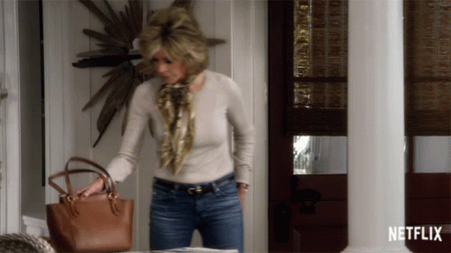 A Woman Holding A Purse In Front Of A Netflix Sign GIF