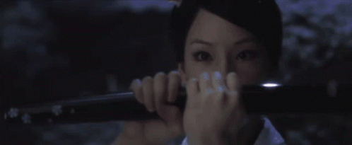 A Woman Holding A Sword In Front Of Her Face GIF