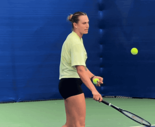a woman holding a tennis racket and a tennis ball on a tennis court