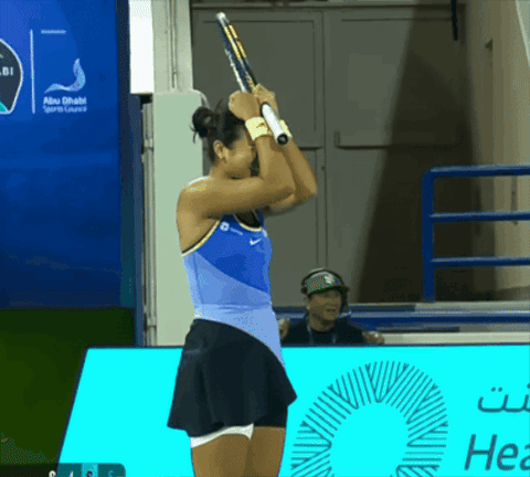 A Woman Holding A Tennis Racket In Front Of An Abu Dhabi Sports Lounge Sign GIF