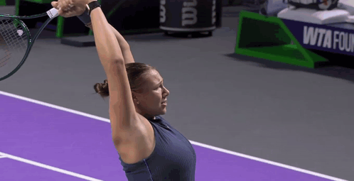 a woman holding a tennis racquet on a purple court