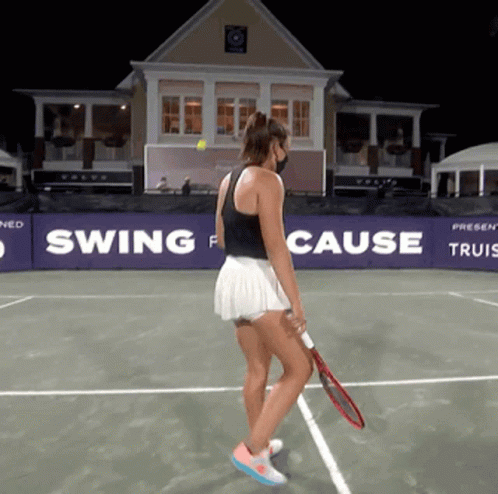 A Woman Holding A Tennis Racquet On A Tennis Court In Front Of A Swing For Cause Banner GIF
