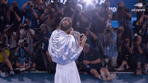a woman holding a trophy in front of a crowd with us open on the screen