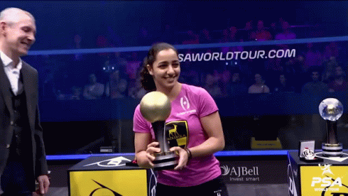A Woman Holding A Trophy In Front Of A Sign That Says ' Saworldtour.com ' GIF