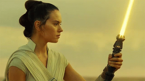 A Woman Holding A Yellow Light Saber In Her Hand GIF