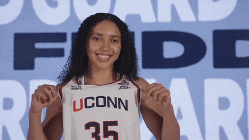 A Woman Holding Up A Uconn Jersey With The Number 35 GIF
