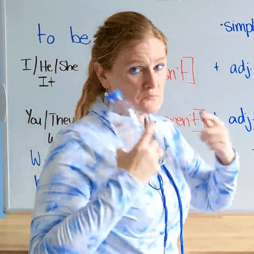 A Woman Holds A Bottle In Front Of A Whiteboard That Says To Be GIF