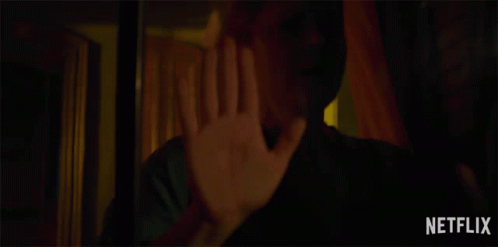 A Woman Holds Her Hand Up In Front Of A Netflix Advertisement GIF