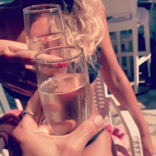 A Woman Holds Up Two Glasses Of Champagne GIF