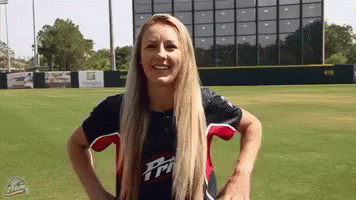 a woman in a baseball uniform is standing on a baseball field .