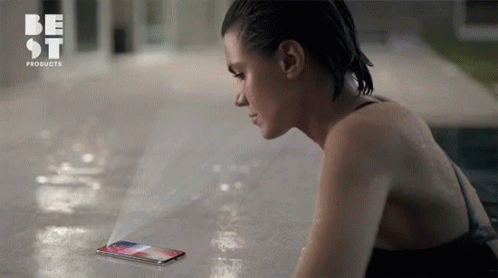 A Woman In A Bathing Suit Is Looking At A Phone That Says Best Products On The Bottom GIF