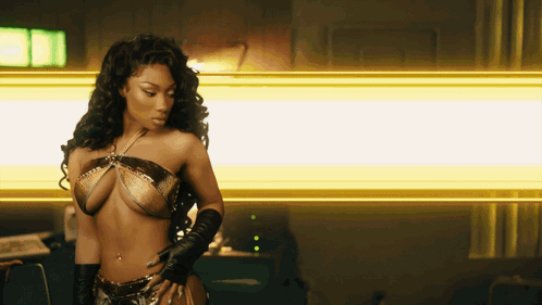 a woman in a bikini and gloves stands in front of a yellow light