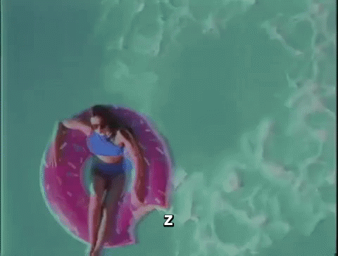 A Woman In A Bikini Is Floating On A Pink Donut Float In A Swimming Pool . GIF