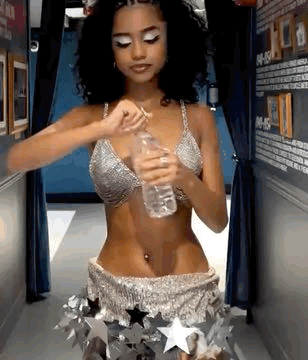 A Woman In A Bikini Is Holding A Bottle Of Water In Her Hand . GIF