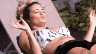 A Woman In A Bikini Is Laying On A Lounge Chair With Her Eyes Closed And Making A Funny Face . GIF