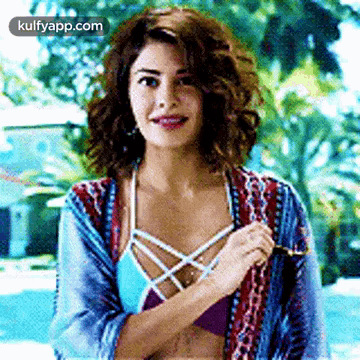 A Woman In A Bikini Is Standing In Front Of A Pool . GIF