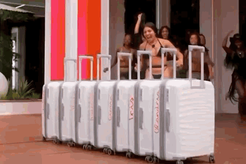 A Woman In A Bikini Is Standing In Front Of A Row Of White Suitcases . GIF