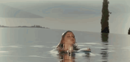 a woman in a bikini is standing in the water .