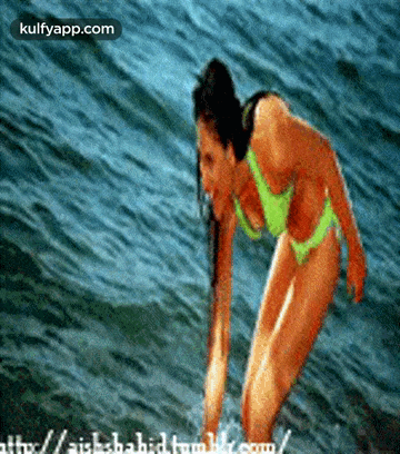 A Woman In A Bikini Is Standing In The Water And The Website Is Kulfyapp.com GIF