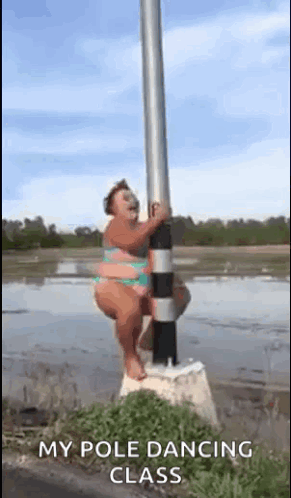 A Woman In A Bikini Is Standing On A Pole In The Water . GIF