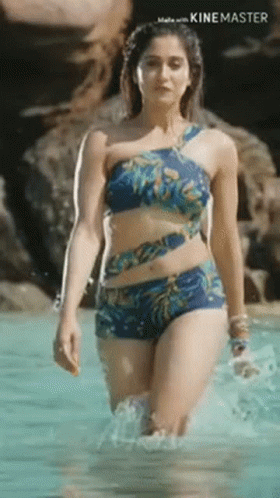 a woman in a bikini is walking out of a pool .