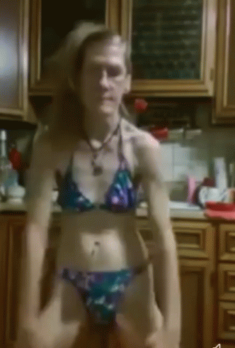 A Woman In A Bikini Sits On A Counter In A Kitchen GIF