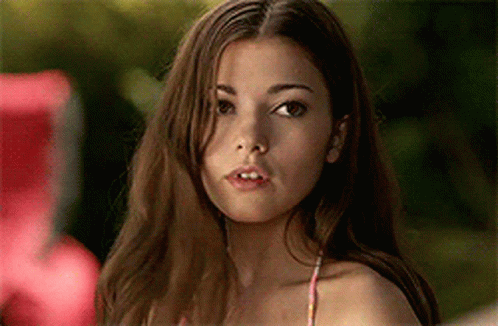 A Woman In A Bikini Top Is Looking At The Camera With A Serious Look On Her Face . GIF