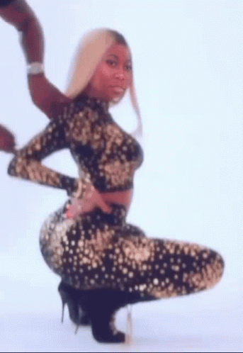 A Woman In A Black And Gold Dress Is Kneeling Down And Holding Her Butt . GIF