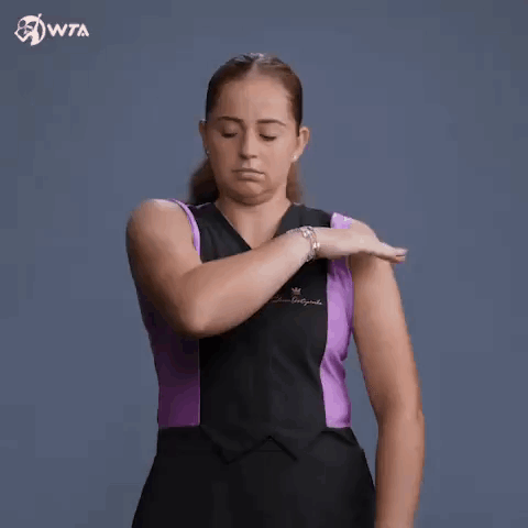 A Woman In A Black And Purple Dress Is Holding Her Arm . GIF