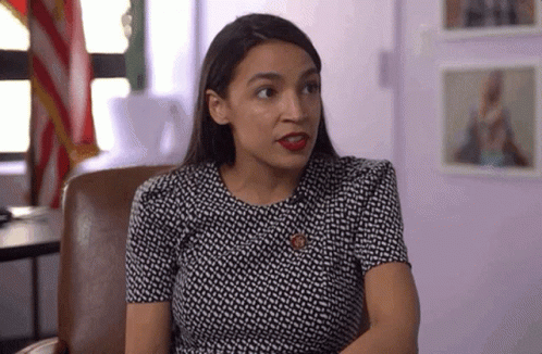 A Woman In A Black And White Dress Is Sitting In A Chair And Looking At The Camera . GIF