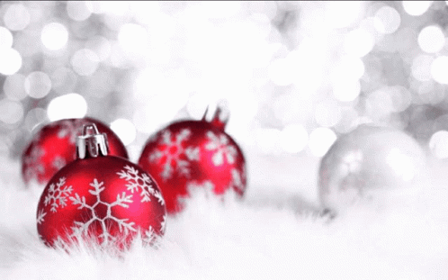 A Woman In A Black And White Floral Shirt Stands In Front Of Christmas Balls GIF
