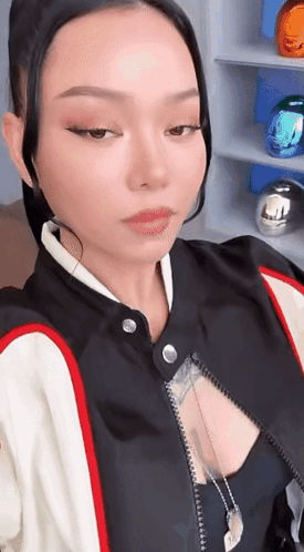 A Woman In A Black And White Jacket Is Taking A Picture Of Herself . GIF